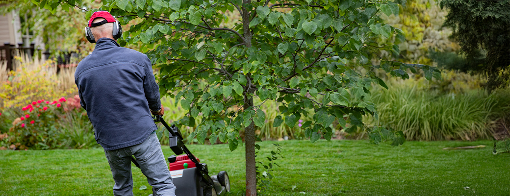 Image of senior man mowing lawn and wearing hearing protection